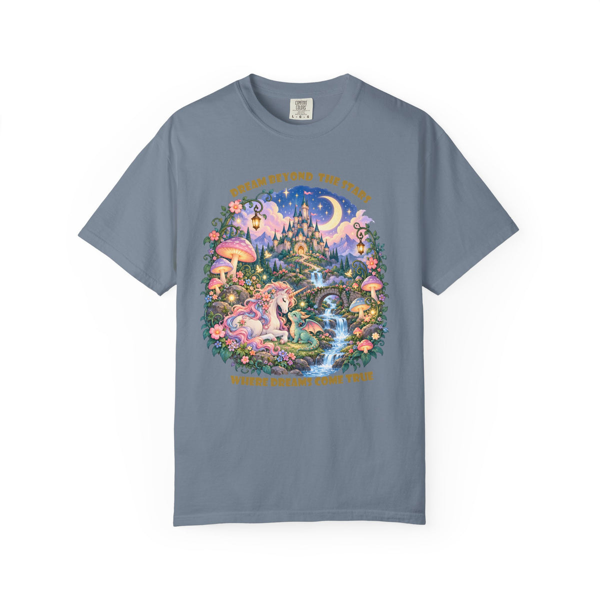 A slate blue short-sleeve t-shirt with a large, colorful fantasy graphic on the front featuring a unicorn, fairies, a castle, and a moon, with gold text reading 'GO BEYOND THE TIES WHERE MIGHT MAKE TRUE' on a white background.